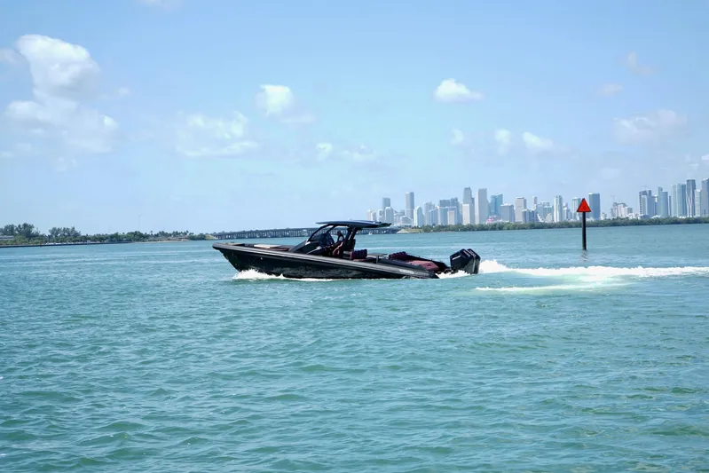  Yacht Photos Pics 2024 Skipper 42 boat cruising on blue water with city skyline in background.