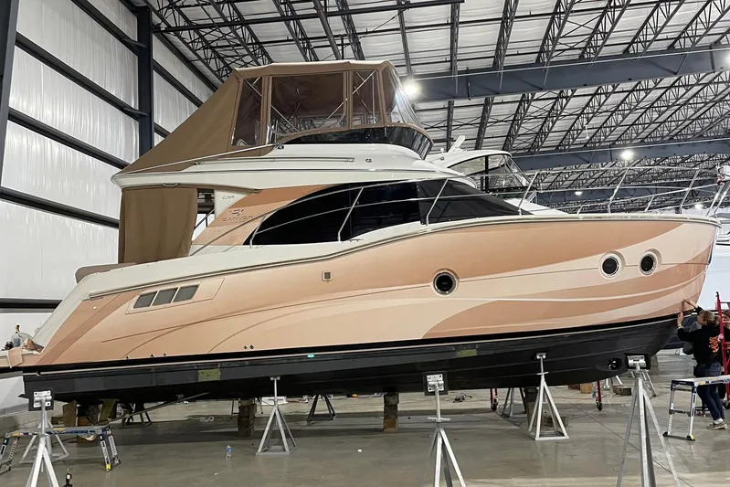 Long Gone Yacht Photos Pics 2013 Carver C34 yacht in a warehouse, elevated on stands, with a beige and white exterior.