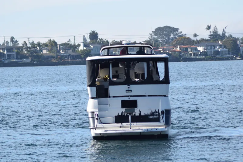 Low Engine Hours Yacht Photos Pics 1995 Cruisers Yachts 3650 ACMY on calm water near residential shoreline.