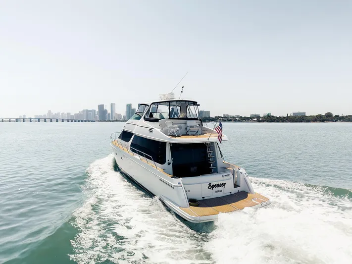 Spencer Yacht Photos Pics 2003 Carver Voyager yacht cruising near city skyline on a sunny day.