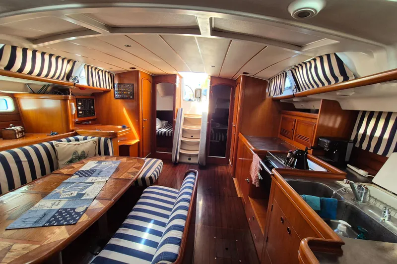 Pac Man Yacht Photos Pics Luxurious interior of 2001 Beneteau Oceanis Clipper 473 yacht with striped upholstery and wooden finishes.