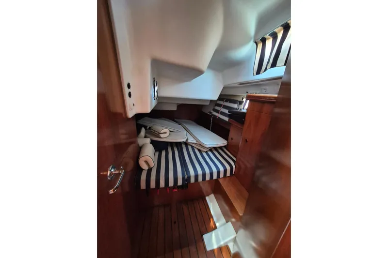 Pac Man Yacht Photos Pics Cozy cabin interior of 2001 Beneteau Oceanis Clipper 473 with striped bedding.