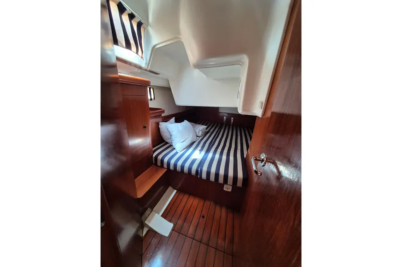 Pac Man Yacht Photos Pics Cozy cabin interior of 2001 Beneteau Oceanis Clipper 473 with striped bedding and wooden finish.