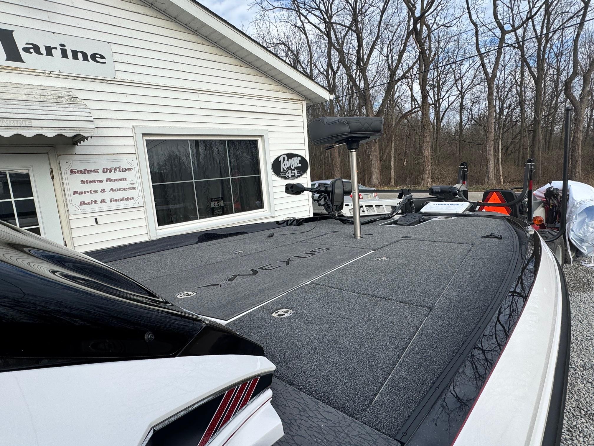 2025 Vexus VXS21 boat parked outside a marine shop in a wooded area.