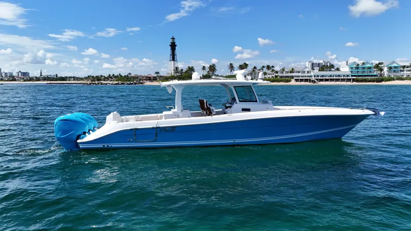  Yacht Photos Pics 2022 HCB Lujo boat on ocean with lighthouse and coastal buildings in background.