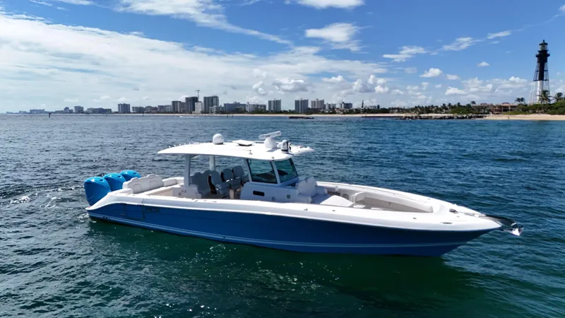  Yacht Photos Pics 2022 HCB Lujo boat cruising near a coastal city skyline and lighthouse.