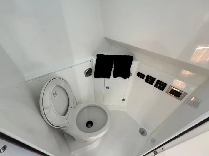  Yacht Photos Pics 2022 HCB Lujo boat bathroom with toilet, black towels, and control panels.