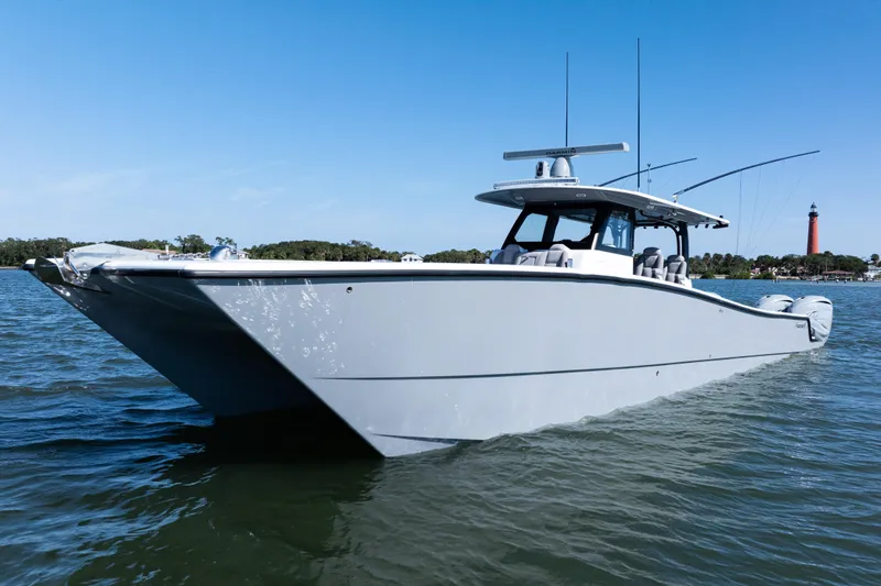  Yacht Photos Pics 2024 Freeman 47 boat on water with lighthouse in background, clear blue sky.