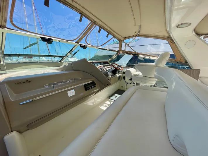 No Doubts IV Yacht Photos Pics 1999 Sea Ray 500 Sundancer cockpit with beige seating and helm, featuring panoramic windows.