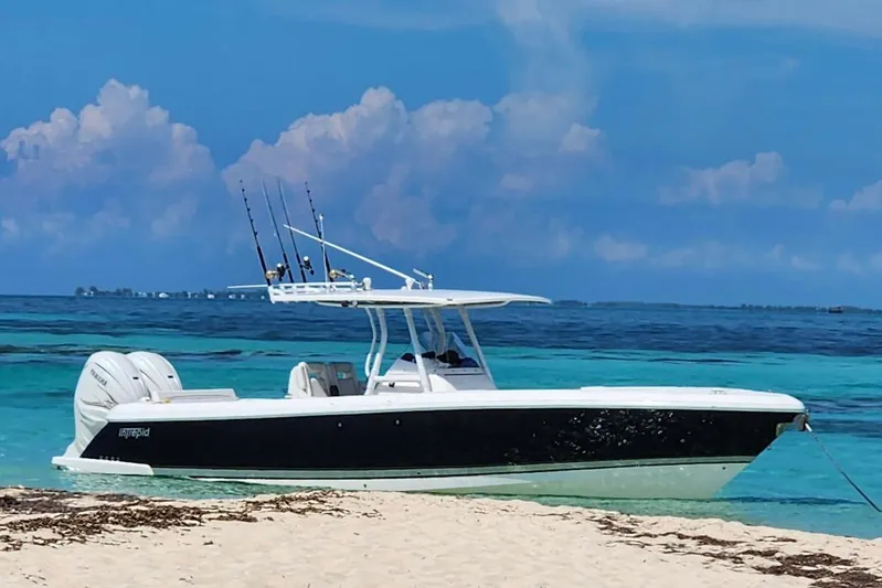  Yacht Photos Pics 2019 Intrepid 345 Nomad FE boat anchored on a sandy beach with clear blue water.