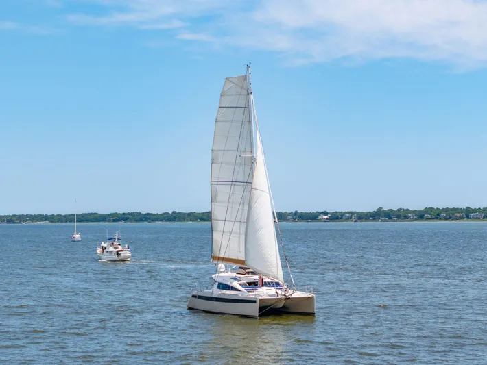 La Cura Yacht Photos Pics 2015 Privilege Series 5 catamaran sailing on a calm lake under a clear blue sky.