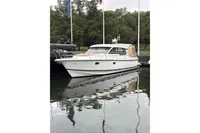 2019 Nimbus 365 Coupe boat docked on calm water, surrounded by trees.