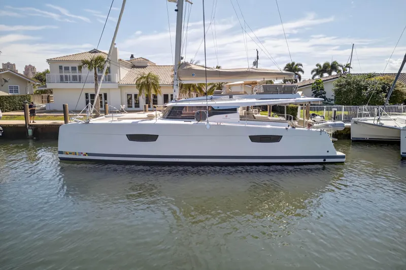 Lucky Dog Yacht Photos Pics 2022 Fountaine Pajot Tanna 47 catamaran docked by waterfront homes.