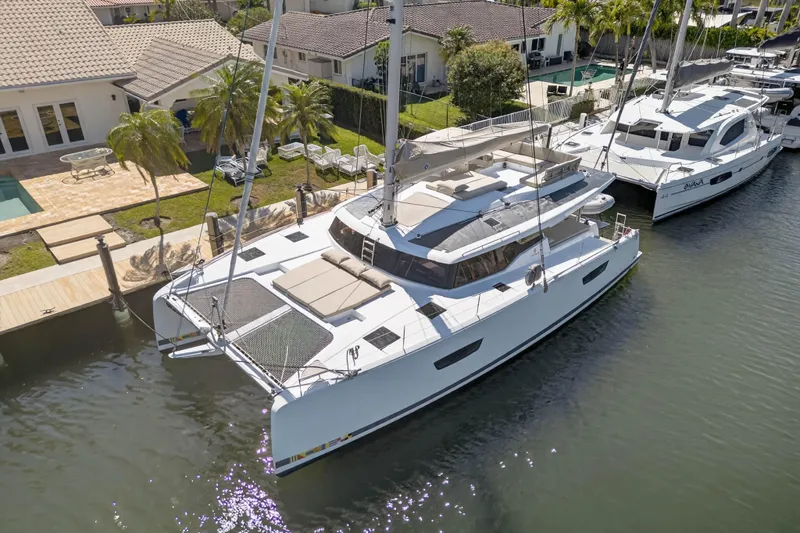 Lucky Dog Yacht Photos Pics 2022 Fountaine Pajot Tanna 47 catamaran docked by waterfront homes.