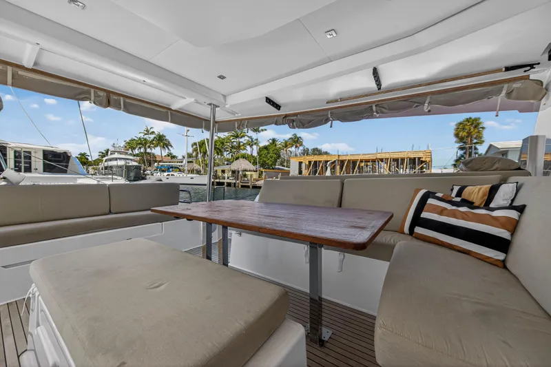 Lucky Dog Yacht Photos Pics Luxurious 2022 Fountaine Pajot Tanna 47 yacht interior with comfortable seating and wooden table.