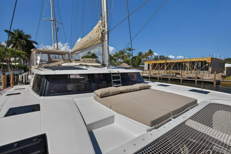 Lucky Dog Yacht Photos Pics 2022 Fountaine Pajot Tanna 47 catamaran docked, featuring spacious deck and sunbathing area.
