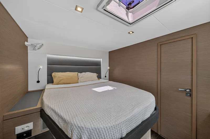 Lucky Dog Yacht Photos Pics Modern bedroom interior on 2022 Fountaine Pajot Tanna 47 yacht, featuring cozy bed and skylight.
