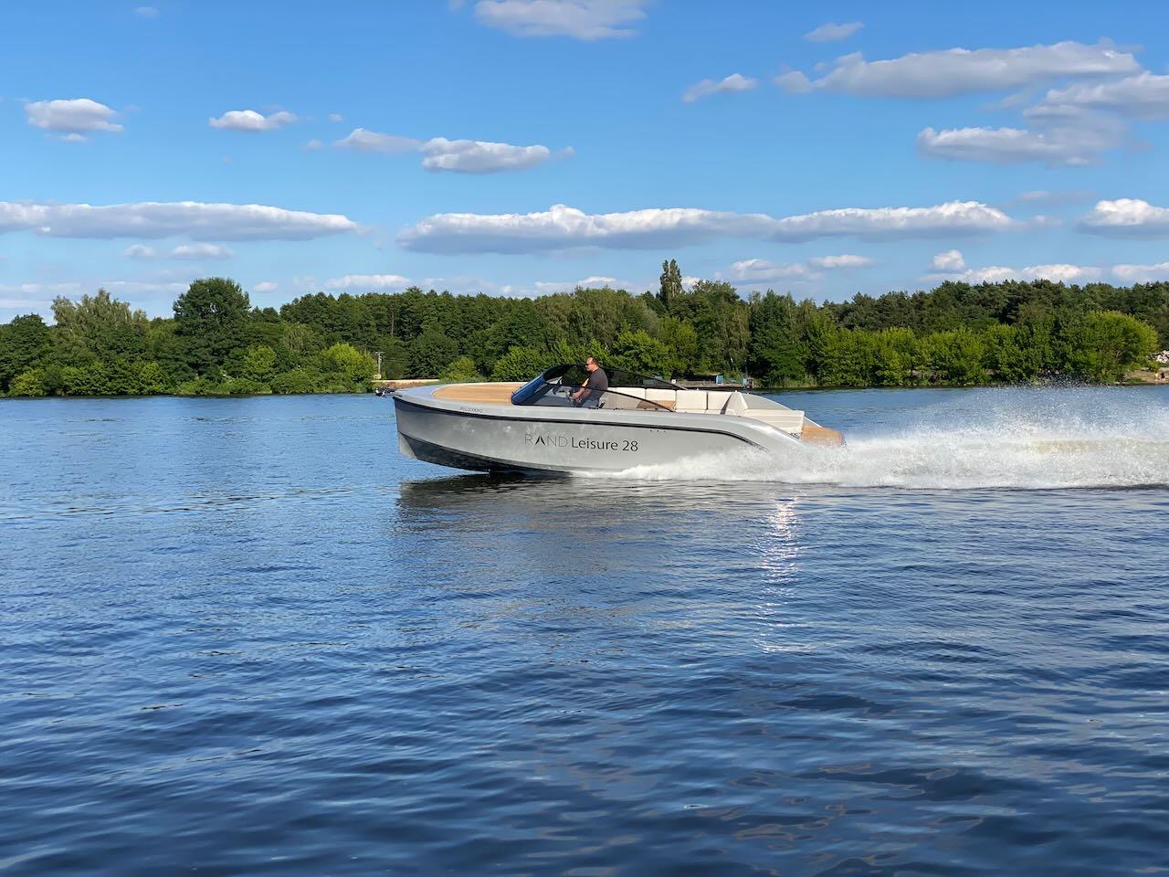 2021 Rand Leisure 28 boat cruising on a lake under a clear blue sky.
