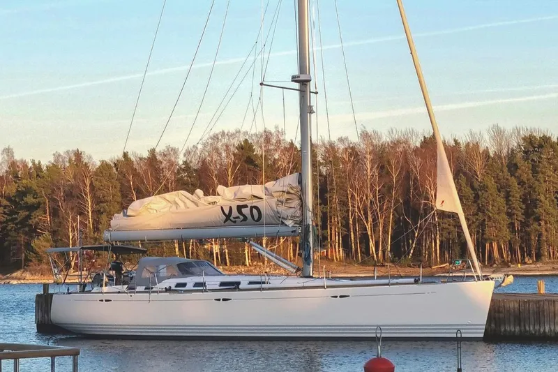  Yacht Photos Pics 2008 X-Yachts X50 sailboat docked by a forested shoreline.