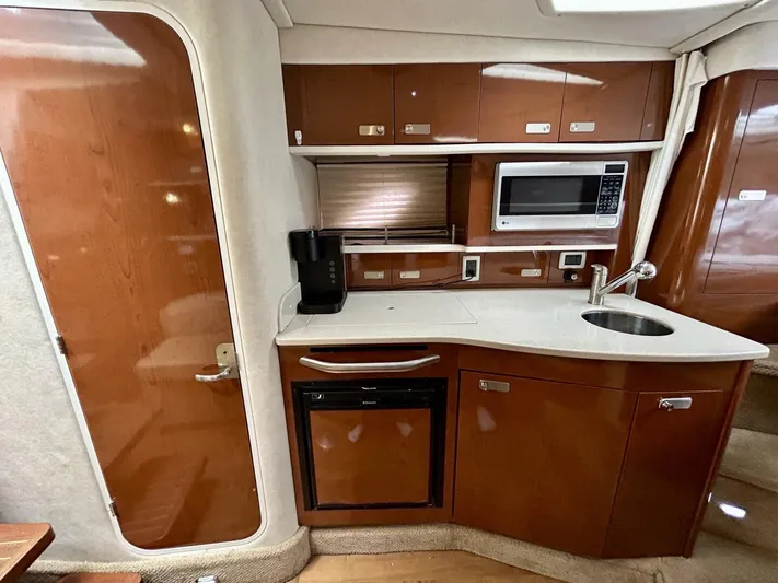  Yacht Photos Pics 2010 Sea Ray 330 Sundancer interior kitchen with microwave, sink, and wooden cabinetry.