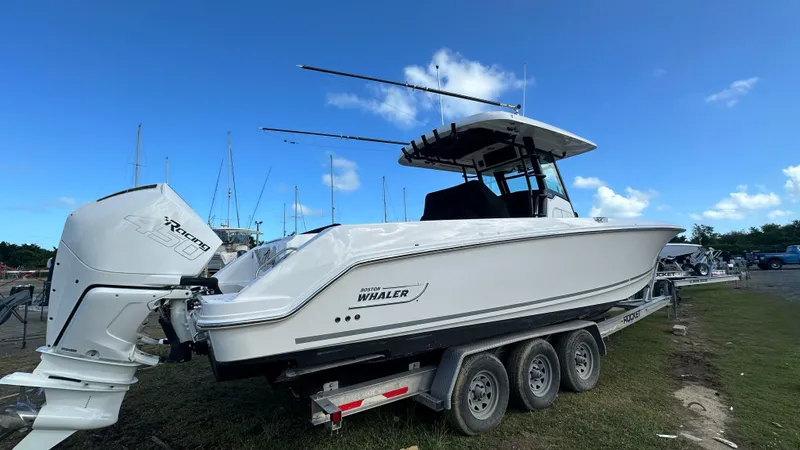  Yacht Photos Pics 2022 Boston Whaler 330 Outrage boat on trailer, side view under clear blue sky.