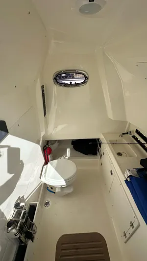  Yacht Photos Pics 2022 Boston Whaler 330 Outrage cabin interior with toilet and porthole window.