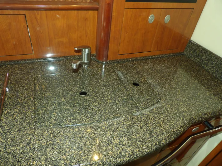 Parrotdise Yacht Photos Pics 2005 Sea Ray 390 Sundancer kitchen sink with granite countertop and wooden cabinets.