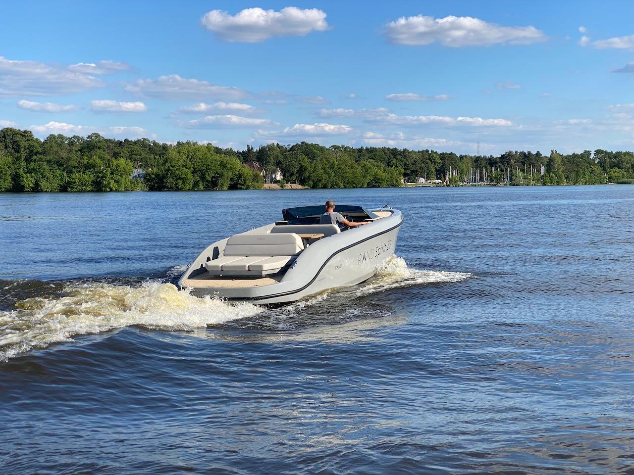 2022 Rand Spirit 25 boat cruising on a lake under a clear blue sky.