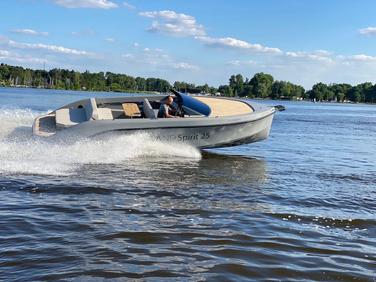 2022 Rand Spirit 25 boat cruising on a lake under a clear blue sky.