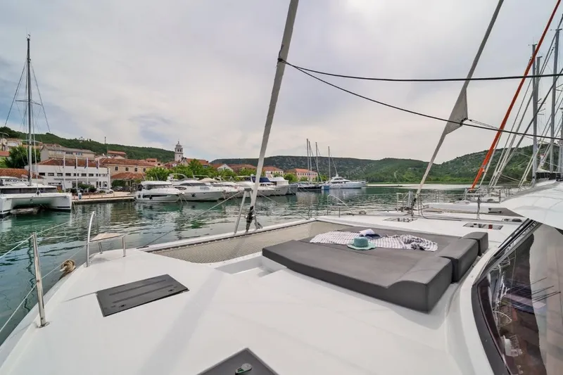 First Life Yacht Photos Pics 2025 Fountaine Pajot Tanna 47 yacht docked in scenic marina with sunbathing area.