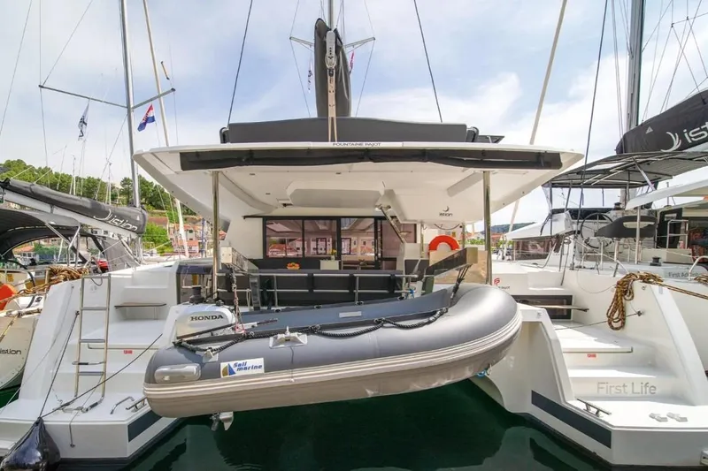 First Life Yacht Photos Pics 2025 Fountaine Pajot Tanna 47 catamaran with dinghy, docked in a marina.