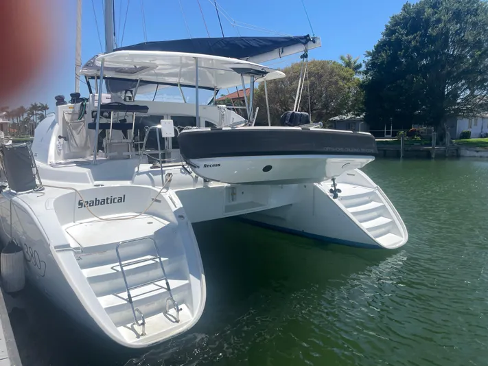 Seabatical Yacht Photos Pics 2016 Lagoon 380 catamaran docked, featuring dual staircases and a small boat on deck.