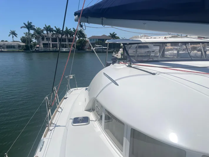 Seabatical Yacht Photos Pics 2016 Lagoon 380 catamaran docked by waterfront homes, under clear blue sky.