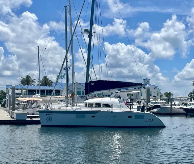 Seabatical Yacht Photos Pics 2016 Lagoon 380 catamaran docked at marina under blue sky and clouds.
