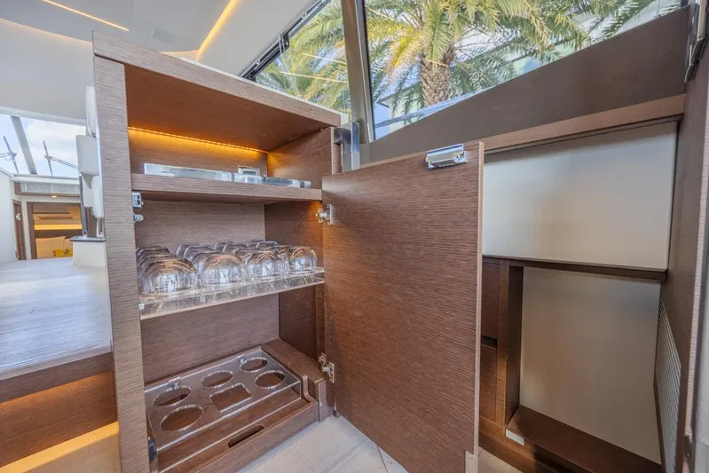 Happy Cay Yacht Photos Pics Luxurious interior of 2021 Prestige 520 Flybridge yacht with open cabinet and glassware.