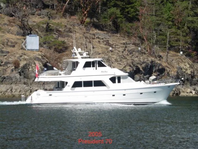 Folie Deux Yacht Photos Pics 2005 President 680 Skylounge yacht cruising near rocky shoreline.