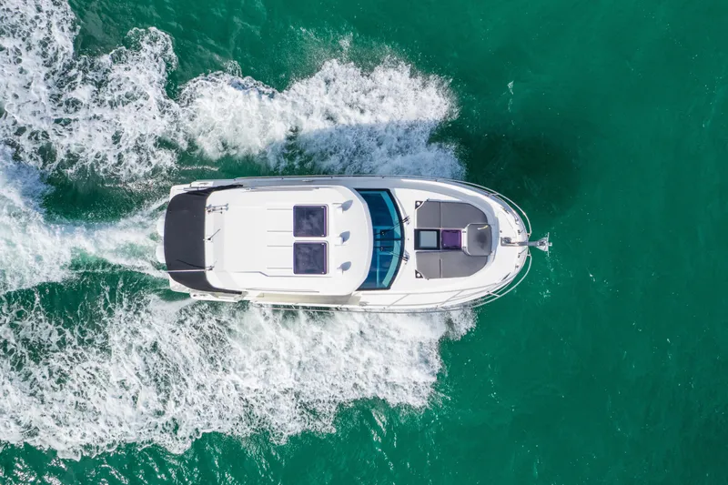  Yacht Photos Pics Aerial view of 2019 Jeanneau NC 1095 cruising on turquoise water.