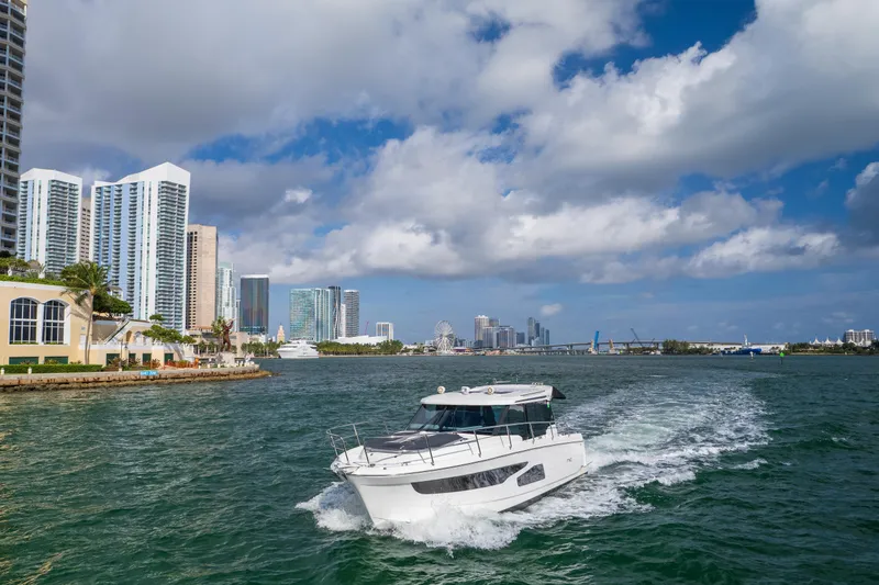  Yacht Photos Pics 2019 Jeanneau NC 1095 cruising near city skyline under cloudy sky.