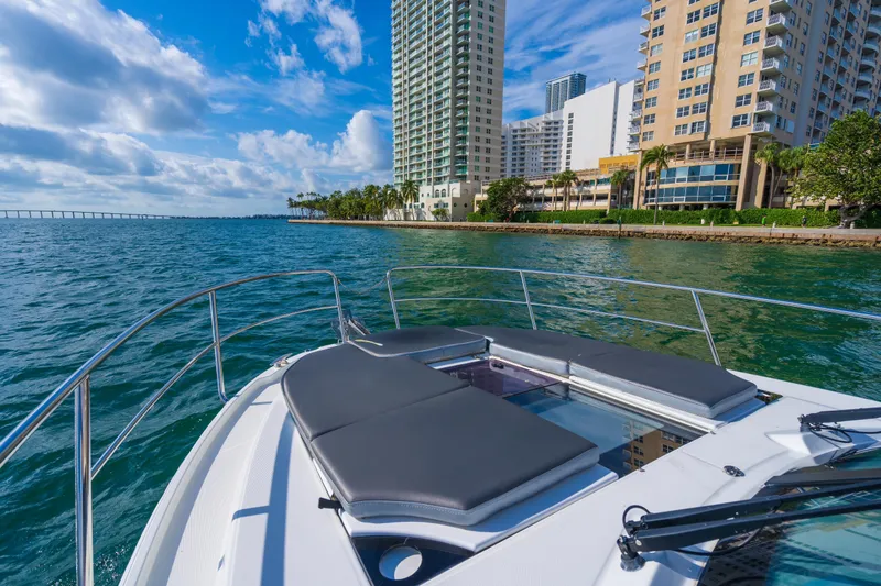  Yacht Photos Pics 2019 Jeanneau NC 1095 boat cruising near city waterfront under blue sky.