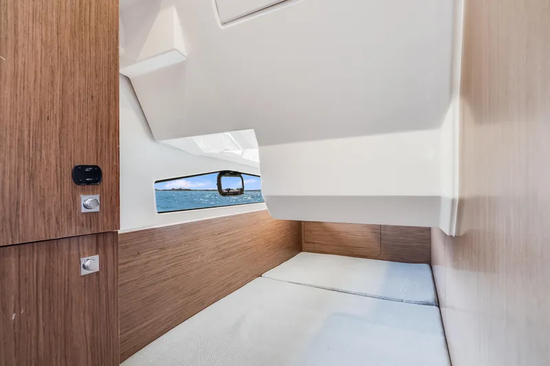  Yacht Photos Pics Interior cabin of 2019 Jeanneau NC 1095 boat with wood paneling and window view.