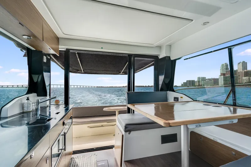  Yacht Photos Pics Interior view of 2019 Jeanneau NC 1095 yacht with kitchen and dining area overlooking water.
