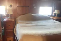 Cozy bedroom interior of 1991 Trader 47 yacht with wooden furnishings and soft lighting.