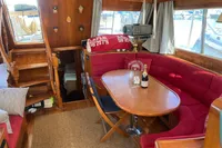 Cozy interior of 1991 Trader 47 yacht with red seating and wooden finishes.