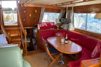 Luxurious 1991 Trader 47 yacht interior with red seating, wooden finishes, and dining area.