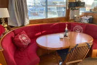 Cozy dining area on 1991 Trader 47 yacht with red seating, table, and champagne.