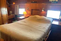 Cozy bedroom interior of 1991 Trader 47 yacht with wooden decor and ambient lighting.