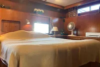 Cozy cabin interior of 1991 Trader 47 yacht with bed, fan, and wooden decor.