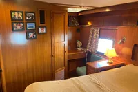 Cozy cabin interior of 1991 Trader 47 yacht with wood paneling and framed photos.