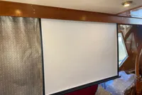 Projection screen inside 1991 Trader 47 yacht, with wooden interior and patterned curtains.