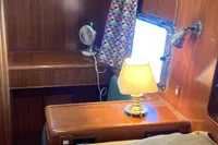 Cozy cabin interior of 1991 Trader 47 yacht with wooden furnishings and a lamp.